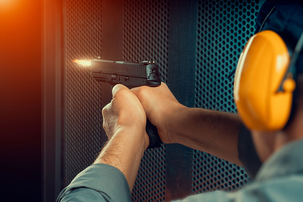 man firing pistol at target indoor shooting range